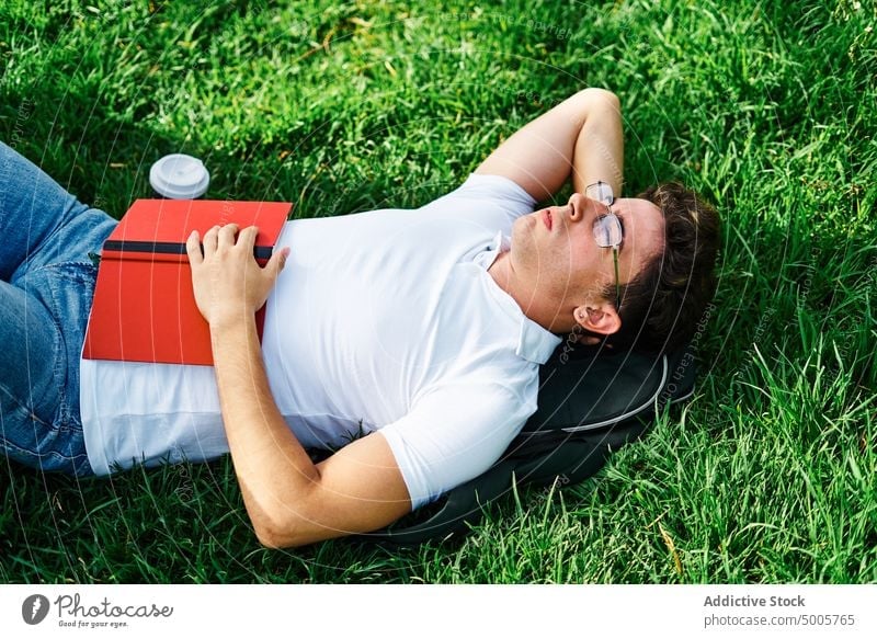 Studentin entspannt mit geschlossenen Augen im Gras Schüler sich[Akk] entspannen Campus ruhen Lügen schlafen Pause Mann Rasen männlich Wiese Natur Park Sommer