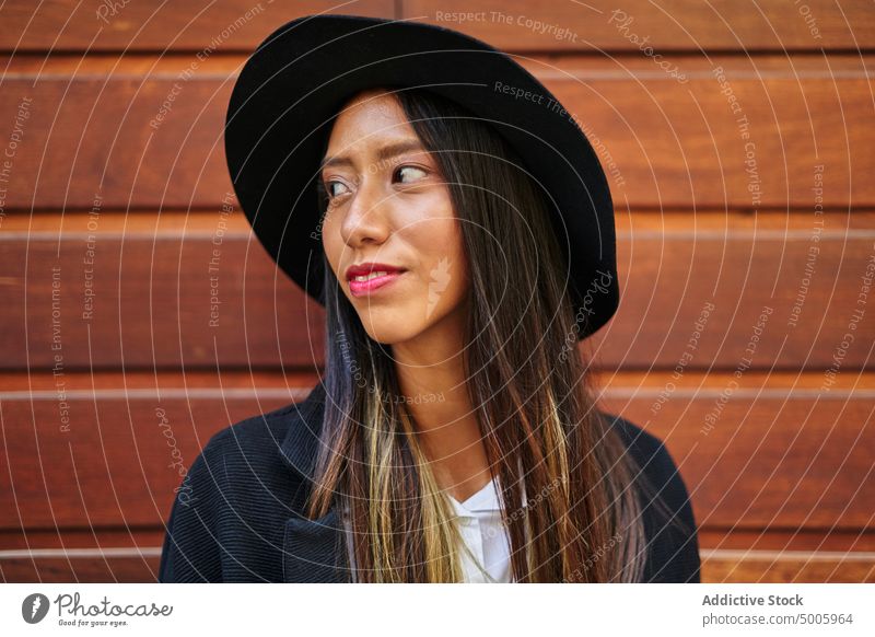 Positive hispanische Frau, die in der Nähe einer Holzwand steht Stil trendy Mode Gebäude Straße Großstadt Outfit Wand hölzern Kleidungsstück Bekleidung Charme