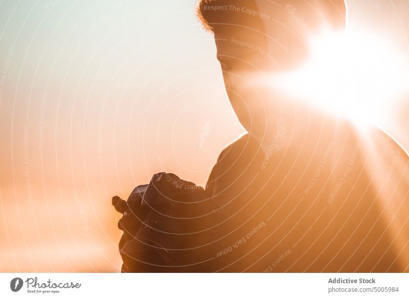 Silhouette eines Mannes im Gegenlicht beim Betrachten von Fotos in seiner Spiegelreflexkamera Fotograf Landschaft Fotokamera Person Abend Licht Himmel reisen