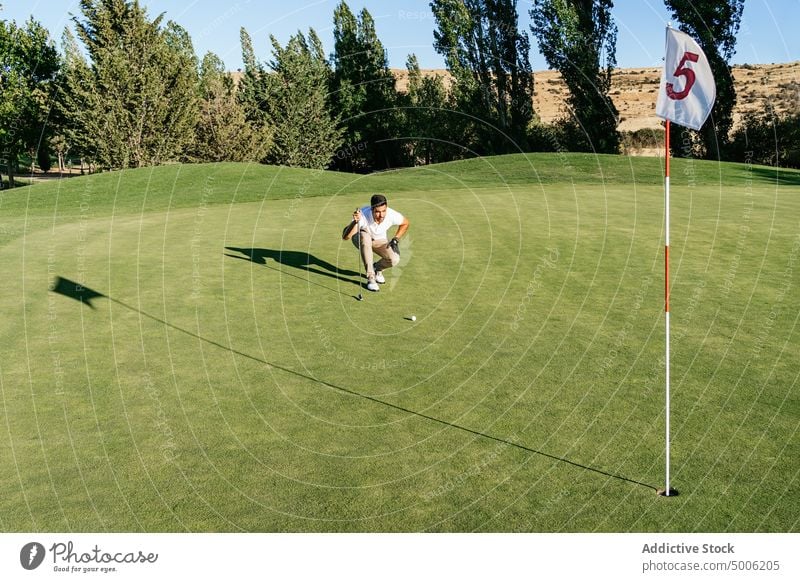 Profigolfer spielt Golf auf dem Platz gegen Bäume Golfer spielen Sport professionell Spiel achtsam Feld Mann Landschaft Gerät Schatten Kniebeuge Fokus Handschuh