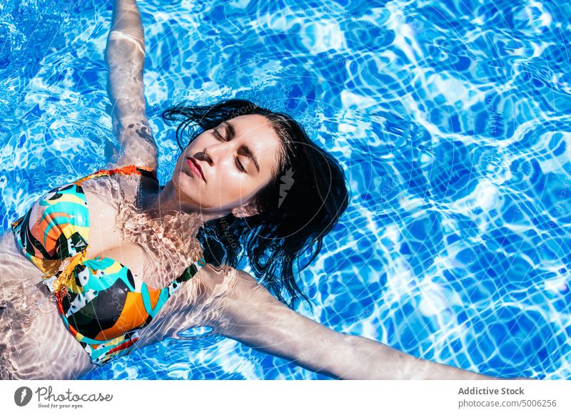Junge Frau entspannt sich im Freibad im Sommer Pool Beckenrand sich[Akk] entspannen Schwimmer Kälte genießen sorgenfrei Wasser Sonnenbad Bikini farbenfroh