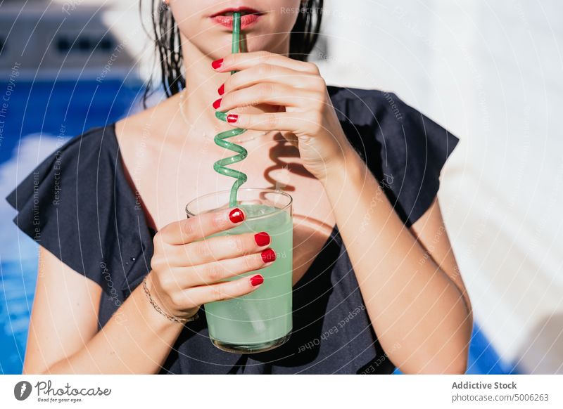 Frau genießt ein kaltes Getränk am Pool Beckenrand trinken aktualisieren Glas Stroh Sommer genießen tropisch grün Sommerzeit Erfrischung Kälte Spirale Resort
