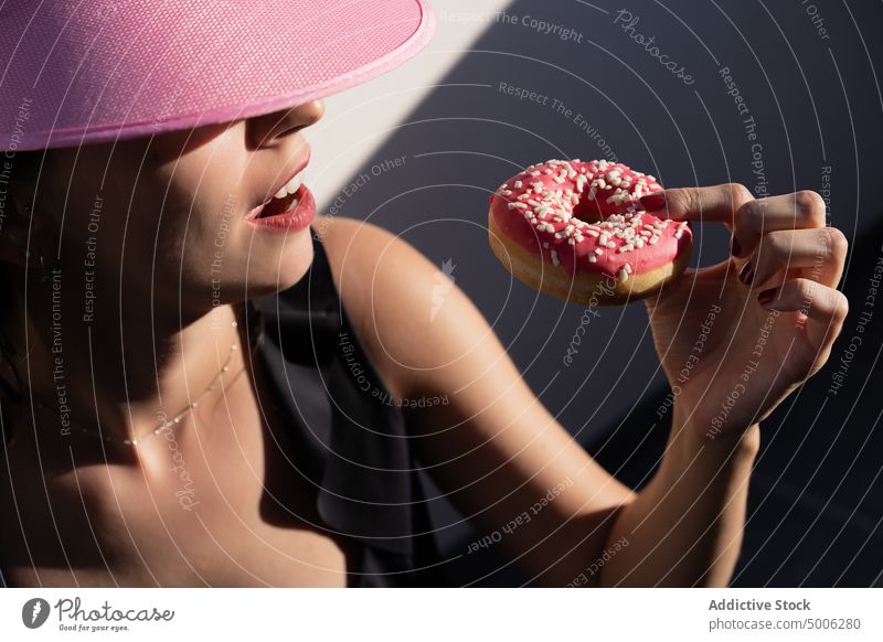 Glückliche Frau isst Donut am Pool Beckenrand Krapfen essen genießen rosa Sommer Sonnenlicht Farbe aufblasbar sorgenfrei jung Schlafmatratze lecker Doughnut
