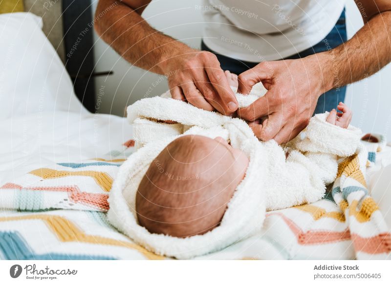Crop Vater Kleidung Baby in warmen Bademantel nach dem Baden in hellen Schlafzimmer sich[Akk] entspannen Dressing frisch Hand Eltern Elternschaft Bett Säugling