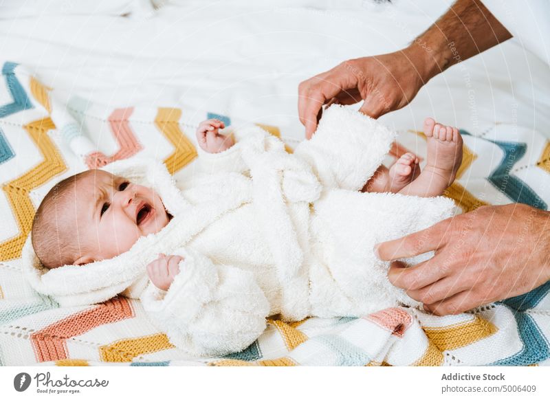 Crop Vater Kleidung Baby weinen in warmen Bademantel nach dem Baden in hellen Schlafzimmer sich[Akk] entspannen Dressing frisch Hand Eltern verärgert