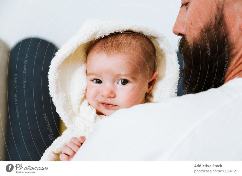 Ruhiger erwachsener Vater trägt süßes Baby auf Händen zu Hause Eltern Papa heimwärts Kind Waschen frisch Dusche Bademantel Säugling neugierig Partnerschaft