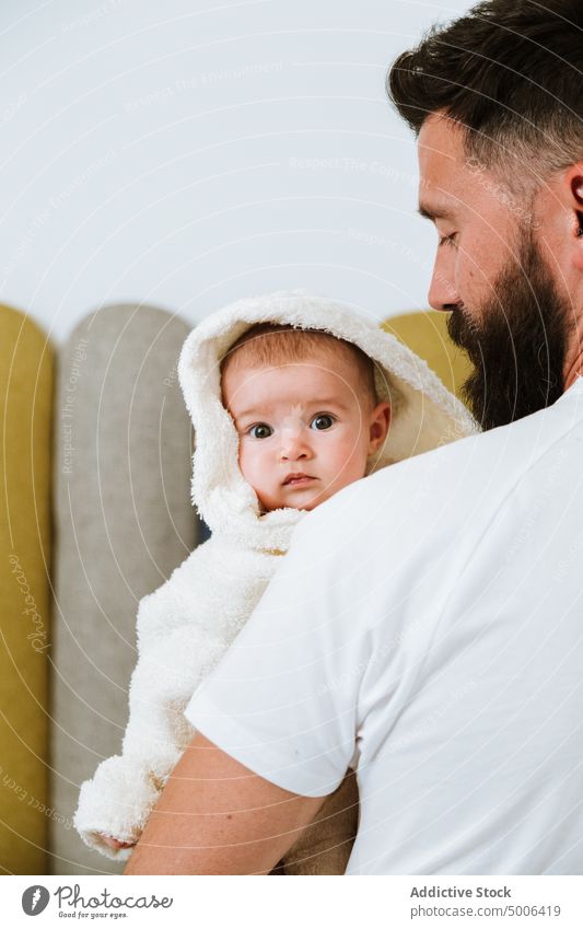 Ruhiger erwachsener Vater trägt süßes Baby auf Händen nach Hause Eltern Papa heimwärts Kind Waschen frisch Dusche Bademantel Säugling neugierig Partnerschaft