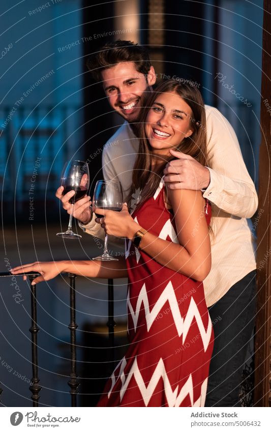 Glückliches Liebespaar trinkt Wein auf dem Balkon Liebhaber trinken anlehnen Freundin Zusammensein Dämmerung genießen Paar romantisch feiern Zuneigung