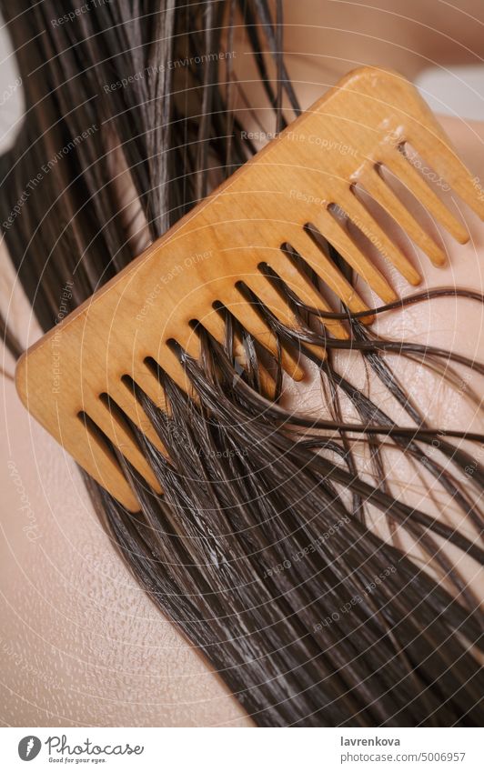 Nahaufnahme eines weiblichen Rückens mit nassen Haarsträhnen, die mit Conditioner und Holzkamm bedeckt sind, Bad hölzern Kamm Schönheit Körper Pflege Sauberkeit