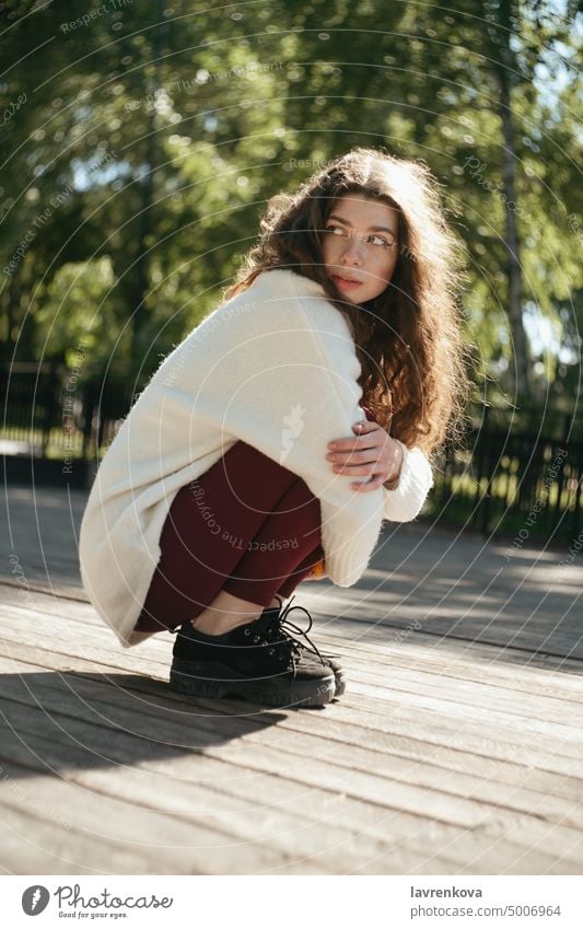 Brünette Frau im weißen Pullover im Park sitzend, selektiver Fokus Erwachsener allein attraktiv Herbst brünett lässig Kaukasier heiter krause Haare niedlich