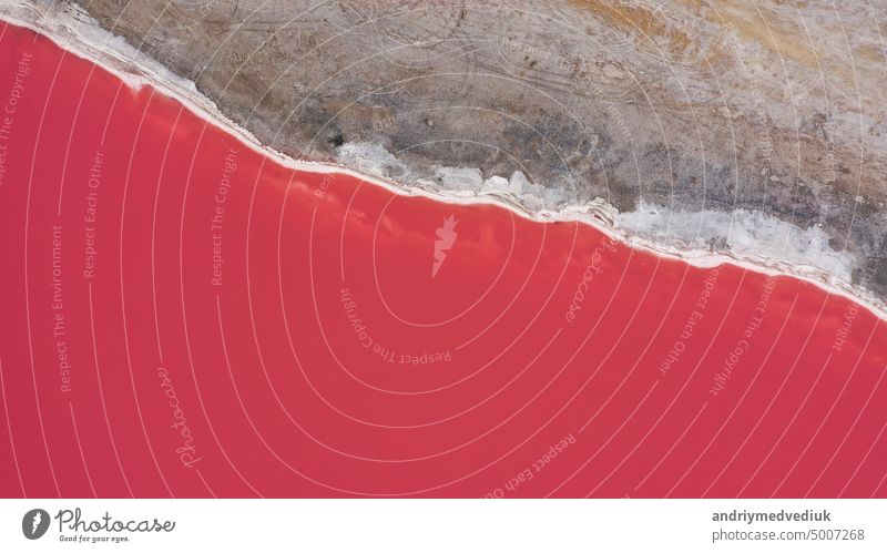 Überfliegen eines rosa Salzsees. Salzproduktionsanlagen salzige Verdunstungsteich Felder in den salzigen See. Dunaliella salina vermittelt ein rotes, rosafarbenes Wasser in einem Mineralsee mit trockener, kristallisierter Salzküste.