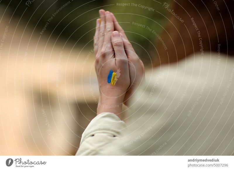 Stoppt den Krieg. Frieden in der Ukraine. Frau Hände mit Bild der Flagge der Ukraine, Hände im Gebet gefaltet. Antikriegsunterstützungskonzept. Hohe Qualität Foto