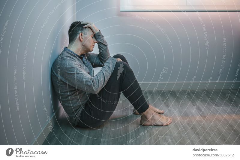 Mann mit Problemen beim Ausruhen auf dem Boden sitzend Typ Stress müde Problematik verzweifelt Kopf aussruhen Waffen Sitzen Stock Textfreiraum