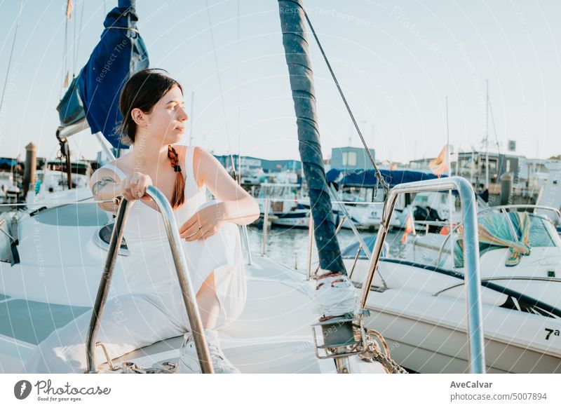 Junge glückliche Frau, die sich auf einem luxuriösen Segelboot während ihres Sommerurlaubs amüsiert. Ruhige junge Frau sitzt auf Segelboot. Getting das Boot bereit zu segeln. Urlaub, Jugend und Spaß Konzept