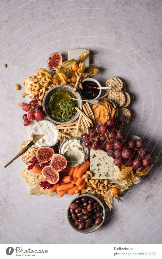 Eine schöne Käseplatte mit Obst, Gemüse, Dips und Nüssen auf einem weißen Hintergrund, vertikal Antipasti Holzplatte Camembert Karotten Käsesorten Cracker