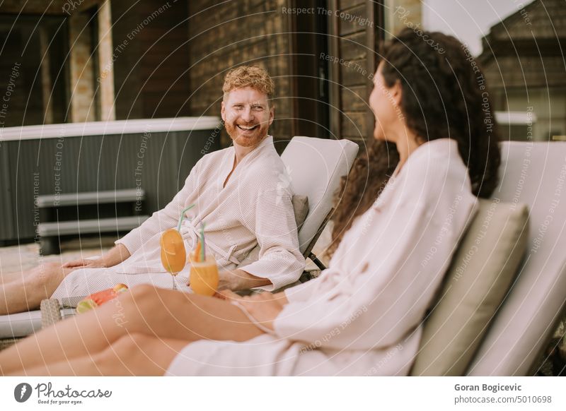 Junges Paar entspannt sich auf den Betten und trinkt frischen Orangensaft auf der Außenterrasse Romantik Kaukasier Glück Zusammengehörigkeitsgefühl Ehemann Frau