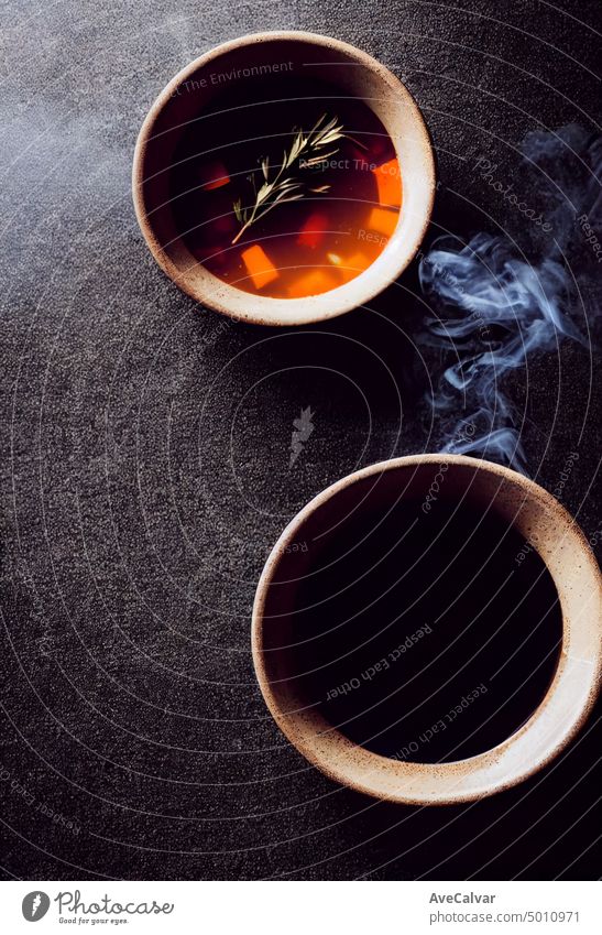Schüssel mit heißem Dampf von heißer Suppe mit Rauch schwarzer Keramikschale auf dunklem Hintergrund heißes Essen kulinarisch Verdunstung Restaurant Licht