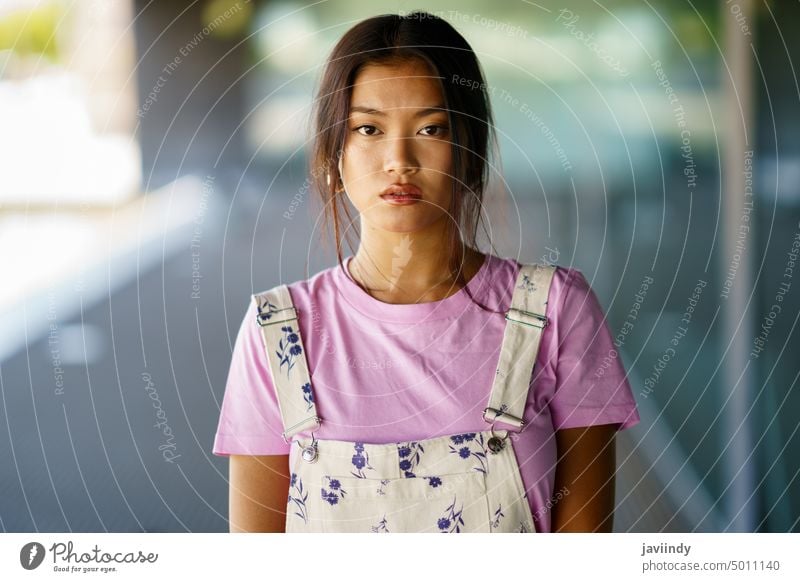 Junge chinesische Frau schaut mit ernstem Gesichtsausdruck in einem modernen Bürogebäude in die Kamera asiatisch Chinesisch Japanisch Mode Person Mädchen