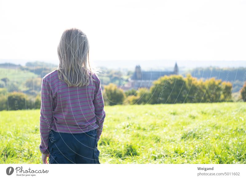 Rückansicht eines jungen Mädchens mit grau pink gestreiftem Pullover, das in die Ferne auf die Comburg in Schwäbisch Hall blickt Landschaft Natur Weitblick