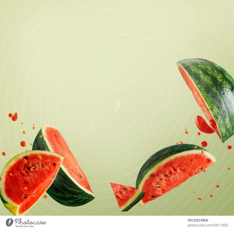 Fliegende Wassermelonenscheiben mit Saftspritzern auf hellgrünem Hintergrund. Kreative Lebensmittel Levitation fliegen Scheiben platschen Licht kreativ Frucht