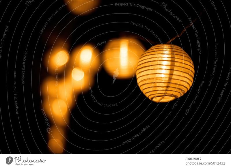 Lampions an einer Kette bei Nacht lichterkette leuchten papierlampe ball orange romantische nacht nächtlich dekoration querformat nahaufnahme tiefenschärfe hell