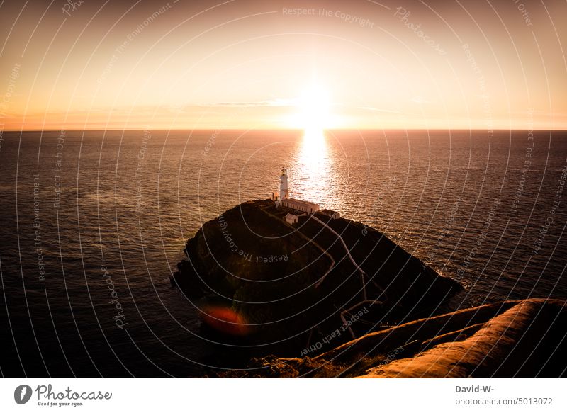 Leuchtturm am Horizont angestrahlt von der untergehenden Sonne Sonnenuntergang Meer wunderschön Sonnenstrahlen golden Licht Sonnenlicht Urlaubsstimmung Küste