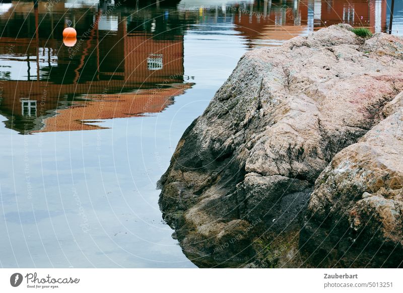 Rote norwegische Holzhäuser spiegeln sich im Wasser, Felsen im Vordergrund, Boje rot Norwegen skandinavisch Spiegelung Skandinavien Norden Küste Hafen still