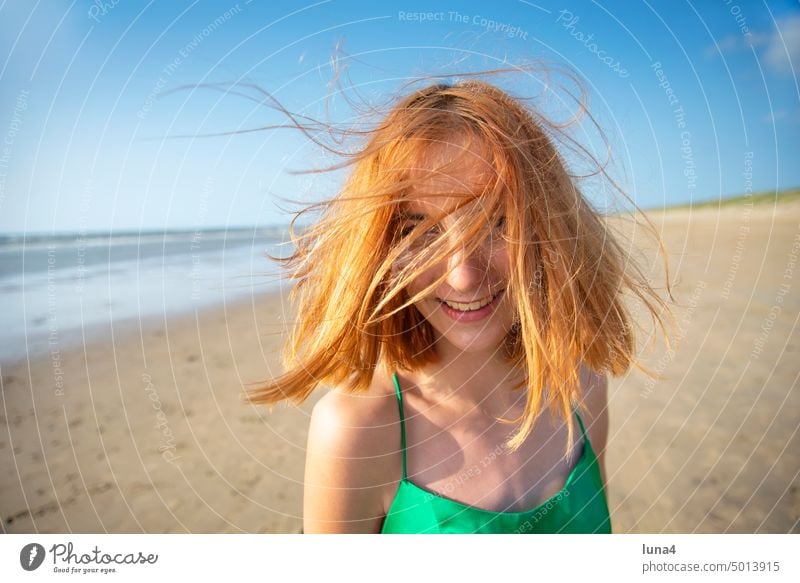 fröhliches Mädchen mit zerzausten Haaren am Strand Meer lachen Glück teenager glücklich Wind windig Sturm Wetter Freude unbeschwert Lebensfreude jung Jugend
