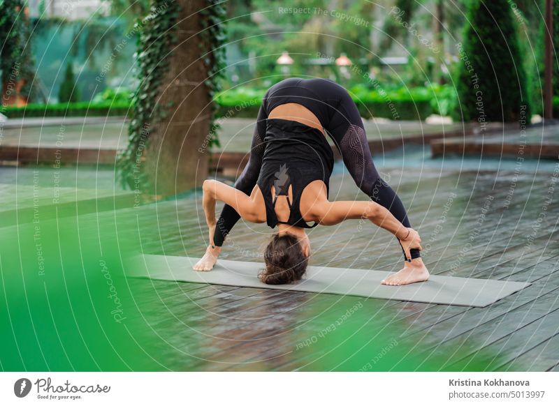 Professionelle Gymnastik Fitness-Lehrer tun Uttanasana stehend barfuß auf Yoga-Matte. Flexible Frau streckt sich nach vorne, Kopf Neigung zu den Beinen. gesunden Lebensstil Konzept