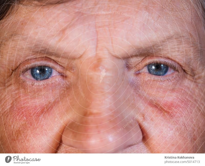 Verengung der Pupille. Schöne blaue Augeniris einer Frau mittleren Alters. Peepers der alten Großmutter mit Falten. schön Nahaufnahme Hornhaut Blickfang