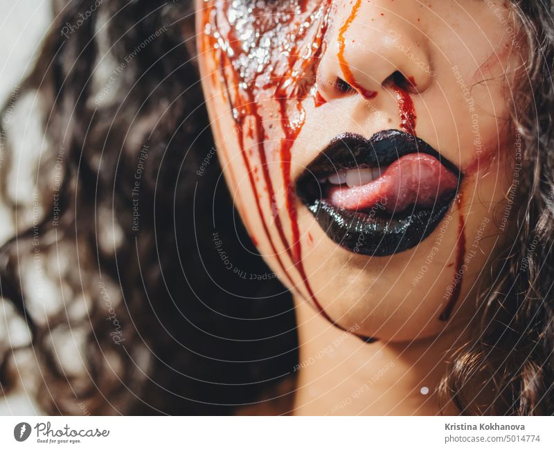 Scary Porträt der jungen Zombie-Frau mit Halloween Blut Make-up. Schönes lateinisch geschlagenes Mädchen mit lockigem Haar schaut in die Kamera. Erwachsener