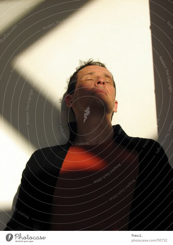 im Sonnenlicht sitzen Meditation Porträt Mann Jacke schwarz Licht genießen träumen Zufriedenheit Physik Winter ruhig Fünfziger Jahre Wohnzimmer Vertrauen orange