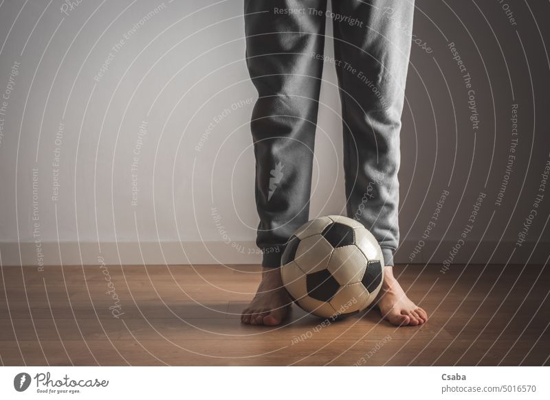 Beine eines Mannes, der vor einem Fußball steht Stehen Raum im Innenbereich Barfuß männlich Ball unkenntlich Erwachsener Person neben Sport weiß Wand Menschen