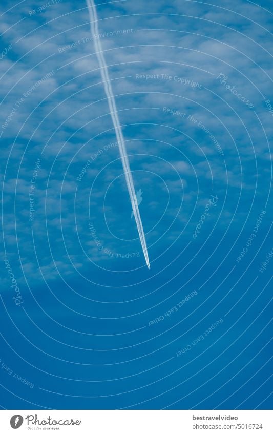 Ein Düsenflugzeug fliegt in einem blauen Himmel und bildet weiße Kondensstreifen. Kondensstreifen von Düsenflugzeugen