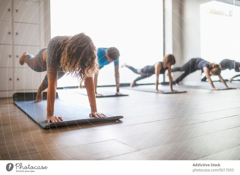 Frau macht Planke während Yoga-Kurs Menschengruppe Klasse Schiffsplanken eka pada phalakasana Ausbilderin üben