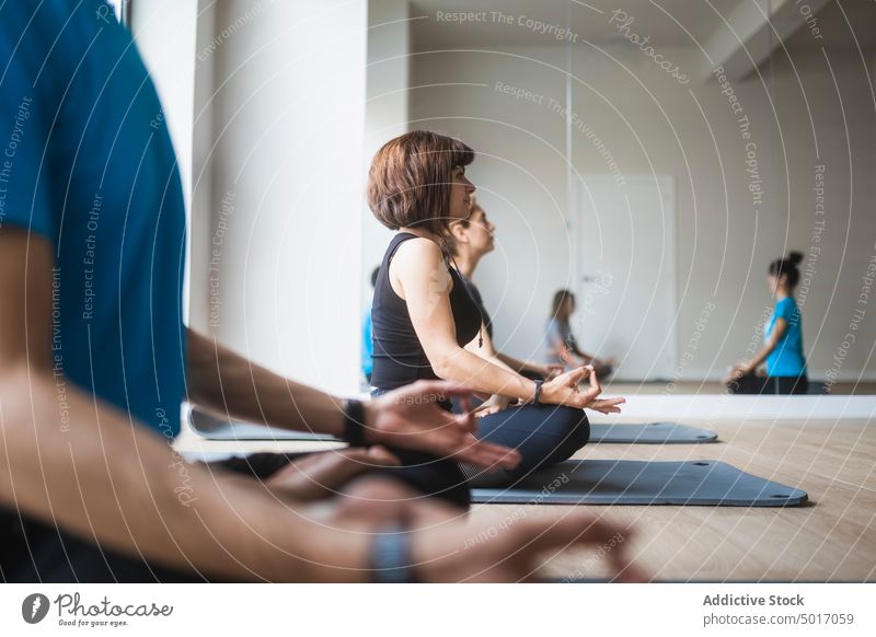 Gruppe von Menschen mit Lehrer übt Yoga im Studio meditieren Ausbilderin Lotus-Pose padmasana Menschengruppe üben Klasse Asana Zusammensein Trainerin Vitalität