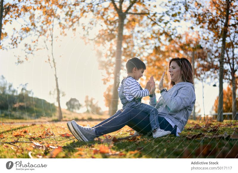 Mutter und Sohn spielen Klatschspiel im Park Klatschen Spiel Kind Hand Spaß haben spielerisch Herbst Junge Zusammensein Glück heiter Liebe Freude Kindheit