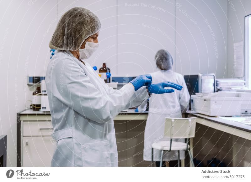 Frau zieht im Labor Handschuhe an arbeiten Wissenschaft anmachend blau Person forschen Wissenschaftler medizinisch Medizin Chemie Technik & Technologie Chemiker