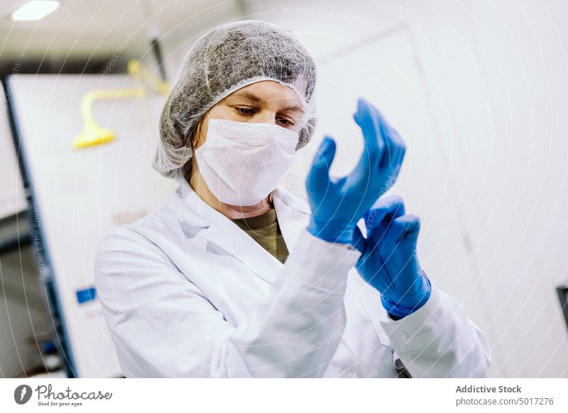 Frau zieht im Labor Handschuhe an arbeiten Wissenschaft anmachend blau Person forschen Wissenschaftler medizinisch Medizin Chemie Technik & Technologie Chemiker