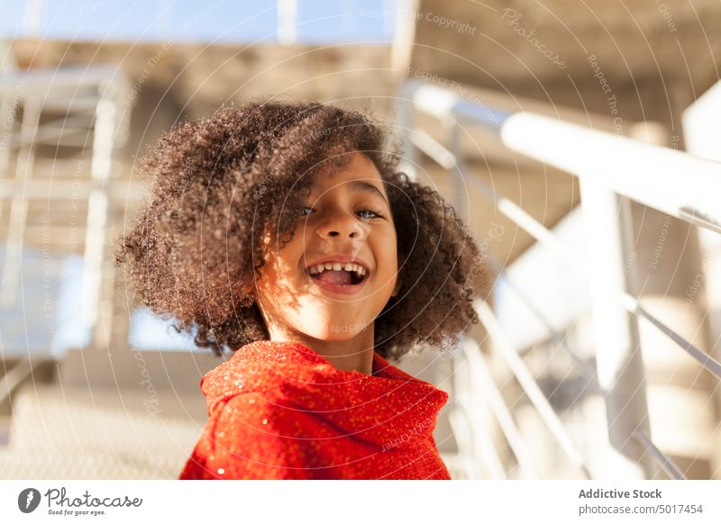 Lächelndes süßes schwarzes Mädchen auf der Straße Sonnenschein heiter Kind Schritt sonniger Tag Afroamerikaner niedlich Glück positiv Spaziergang Großstadt