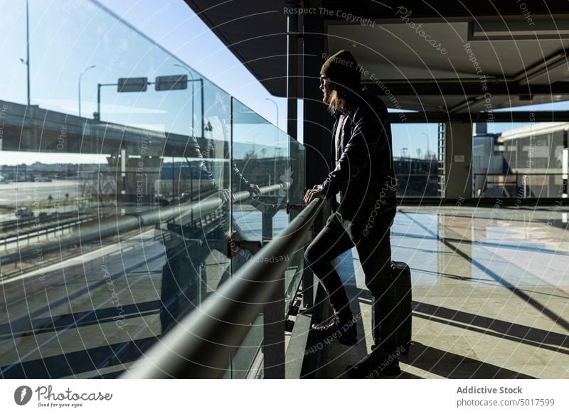 Hipster-Mann mit Gepäck im Flughafen reisen Passagier Koffer warten Laufband trendy Stil modern schwarz männlich Hut Lederjacke Ausflug Reise Urlaub Tourismus