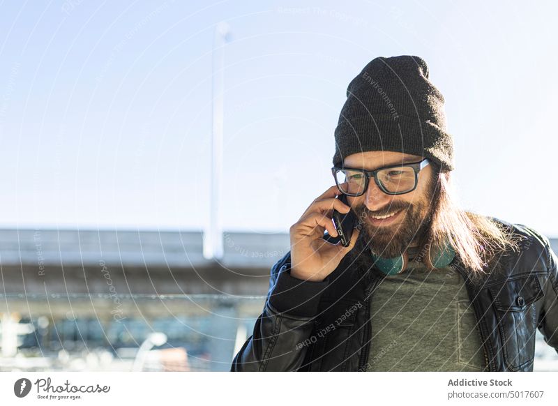 Hipster-Mann telefoniert auf einem Flughafen Telefon reden reisen Passagier trendy Stil Smartphone Erwachsener Lächeln positiv modern ernst männlich Vollbart