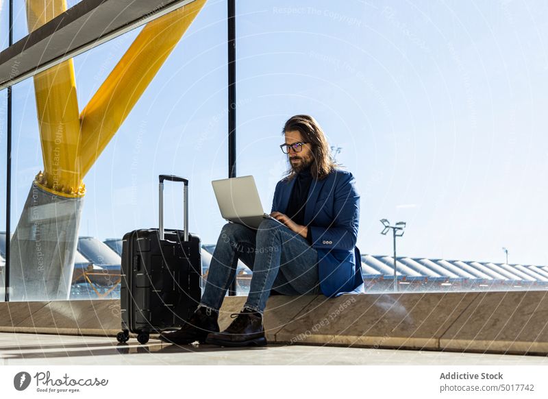Beschäftigter Mann mit Laptop in der Flughafen-Lounge trendy benutzend Stil Business Ausflug beschäftigt Arbeit Koffer reisen Passagier Gerät Apparatur