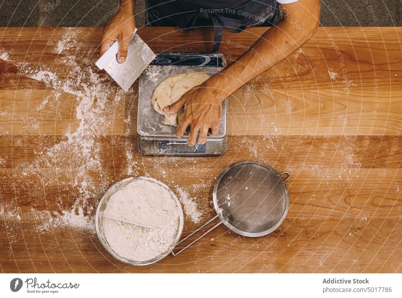 Erntekoch wiegt Teig Bäckerei Gewicht Teigwaren Koch Mann roh Skala Prozess Brot männlich vorbereiten hölzern Tisch Küche kulinarisch frisch Bestandteil Mehl