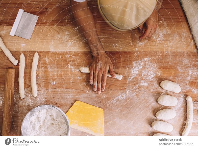 Männlicher Koch, der Teig in einer Bäckerei formt Teigwaren Mann Prozess Form vorbereiten Tisch Uniform männlich Küche Lebensmittel hölzern Gebäck frisch