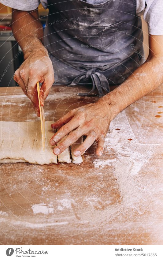 Männlicher Koch schneidet Teig auf dem Tisch geschnitten Teigwaren roh Spielfigur Mann Bäckerei Prozess männlich Schürze hölzern Gebäck Arbeit Küche