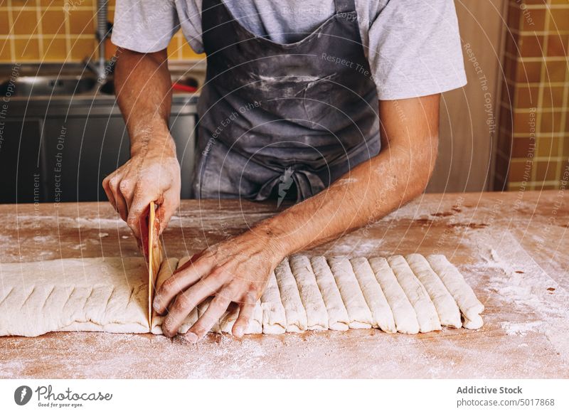 Männlicher Koch schneidet Teig auf dem Tisch geschnitten Teigwaren roh Spielfigur Mann Bäckerei Prozess männlich Schürze hölzern Gebäck Arbeit Küche