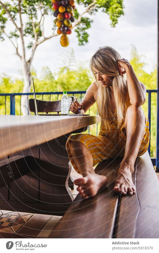 Positive Frau mit Smartphone und Laptop auf der Terrasse benutzend Veranda Garten positiv Sommer Browsen lässig Funktelefon jung Park Gerät Apparatur Mobile