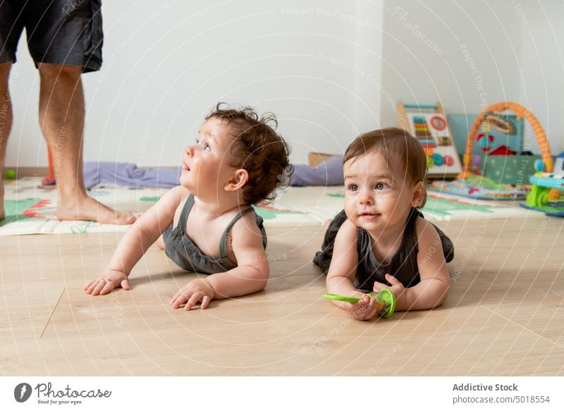 Niedliche glückliche Zwillingsbabys auf dem Boden liegend und mit Spielzeug spielend Kinder Lügen Stock Geschwisterkind Baby bezaubernd Lächeln Glück ähnlich