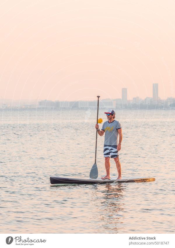 Mann mit Paddel auf Surfbrett auf hoher See Surfen MEER Meer Wasser aktiv Urlaub Sommer männlich Lifestyle extrem winken Abenteuer Erholung Athlet Sommerzeit